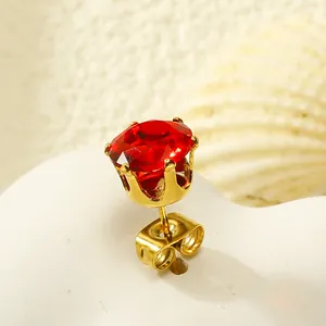 Vue macro de boucles d'oreilles couronne dorées avec pierre zircon rouge et fermoir papillon