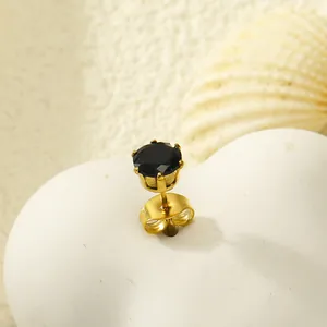 Vue macro d'une boucle d'oreille couronne dorée à six griffes avec zircon noir rond