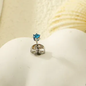 Détail d'une puce d'oreille en zircon bleu avec serti à six griffes sur fond de coquillages
