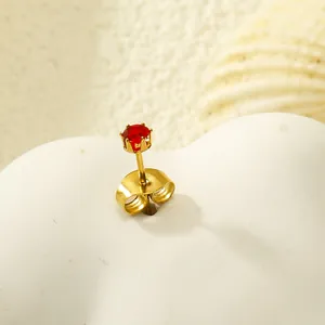 Vue macro d'une boucle d'oreille couronne dorée ornée d'un zircon rouge étincelant