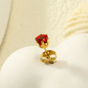 Gros plan d'une boucle d'oreille couronne en acier doré avec zircon rouge et fermoir