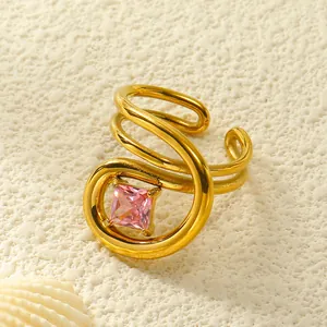 Makroaufnahme Goldener Spiralring mit quadratischem rosa Edelstein und Muscheldeko