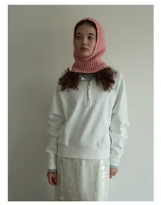 Detalle del pasamontañas de lana rosa con una sudadera blanca con cremallera y falda