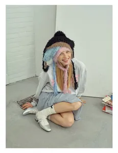 Detail of colorful tiered winter knit beanies with warm earflaps on a fashion model