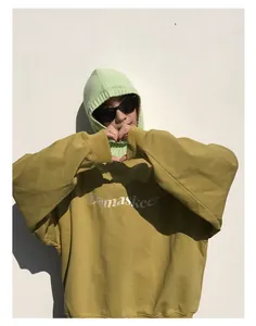 Detalle de un pasamontañas de lana verde claro combinado con una sudadera amarillo mostaza