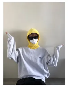 Detalle del pasamontañas de punto amarillo con sudadera gris para un estilo callejero