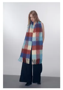 Detailed view of the thick wool blend scarf featuring blue and red check pattern and tassels