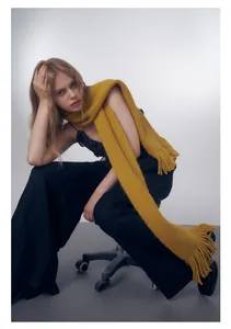 Dettaglio della sciarpa in maglia giallo zenzero con frange spesse e trama fatta a mano