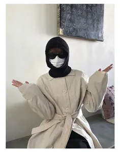 Detalle del pasamontañas de lana negra tejida combinado con una gabardina beige