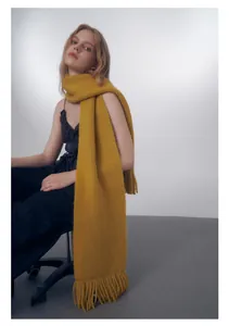 Dettaglio della sciarpa a maglia grossa giallo brillante con lunghe frange e trama spessa