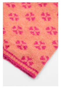 Detailed macro view of high-quality orange knit fabric with pink floral jacquard pattern