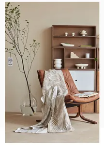 Detail of Nordic jacquard knit blanket with leaf pattern on brown leather chair