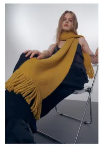 Dettaglio della sciarpa in maglia giallo zenzero con trama spessa e lunghe frange