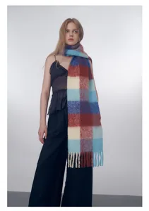 Detail of oversized fuzzy wool plaid scarf featuring blue and brown checks with fringe edges
