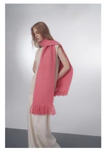 Dettaglio di sciarpa rosa in maglia spessa con lunghe nappe e trama morbida