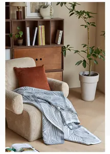 Close-up of Nordic leaf pattern knit blanket draped over a cozy corduroy armchair