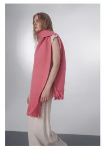 Dettaglio di sciarpa rosa in maglia con trama di lana spessa e lunghe frange decorative