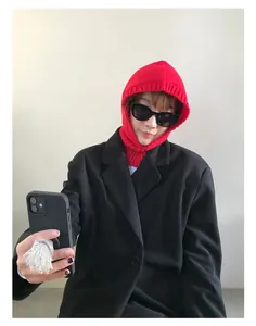 Detalle del pasamontañas de lana roja con textura de punto acanalado en modelo con gafas