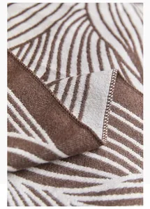 Close-up of Nordic leaf jacquard knit blanket showing texture and overlocked edge