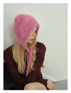 Detailed texture of pink plush knit earflap hat with colorful specks and long ties