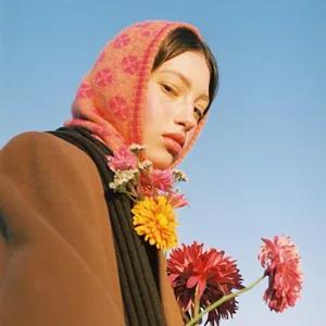 Pink clover knit balaclava hat for women styled with wool coat under a blue sky