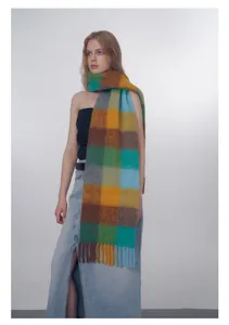 Detail of thick wool blend scarf featuring colorful gradient plaid and long fringe tassels