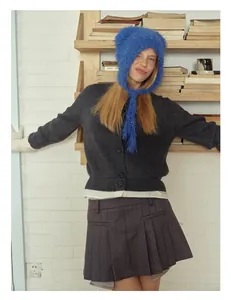 Detail view of a bright blue plush bear ear beanie paired with a gray knit cardigan