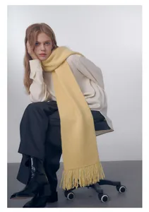 Dettaglio di una sciarpa a maglia giallo chiaro con frange morbide e trama accogliente