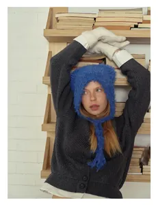 Detail of blue plush earflap hat with knit straps and grey wool cardigan