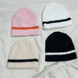 Flachbild von bunten, flauschigen, gestreiften Strickmützen in Pink, Weiß und Schwarz