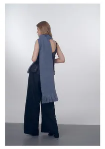 Dettaglio di sciarpa in maglia blu con lunghe nappe a frangia e consistenza morbida