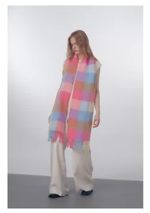 Close-up of wool blend scarf featuring soft gradient plaid patterns and chunky fringe