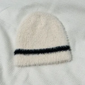 Detailansicht der weichen beigen Strickmütze aus Webpelz mit schwarzen Kontraststreifen