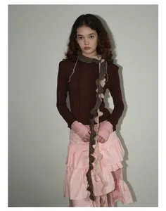 Detalle de bufanda de mohair con bordes ondulados, flecos y falda rosa de volantes