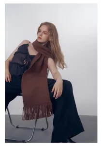 Dettaglio della sciarpa in maglia marrone scuro con nappe per un morbido look invernale
