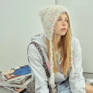 Beige fuzzy knit beanie with ear flaps and long tassels for a modern cozy winter look