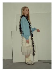 Detalle de bufanda de lana mohair con punto trenzado y flecos sobre un suéter azul