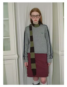 Detail shot of a blue striped wool blend scarf paired with a grey crewneck sweatshirt