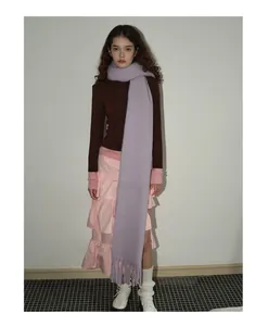 Detailansicht eines lavendelfarbenen Wollschals mit dicken Fransen am modischen Outfit