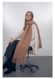 Dettaglio di una lunga sciarpa in maglia color cammello con frange decorative per l'inverno
