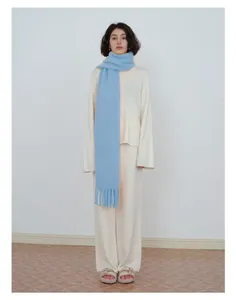 Full view of model wearing a light blue wool blend scarf with fringe and cream outfit