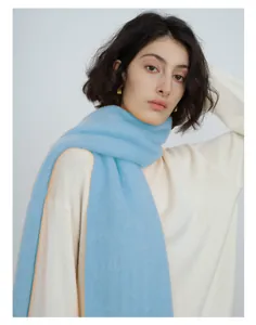 Close-up of soft wool blend knit scarf in light blue with orange contrast edge detail