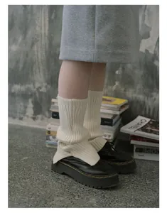 Detail of cream cable knit leg warmers paired with black platform leather shoes