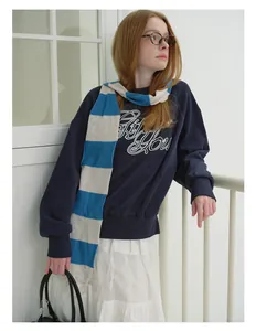 Chic styling view of a blue striped wool blend knitted scarf with a slogan sweatshirt