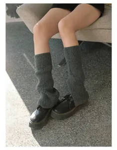 Close-up of dark grey ribbed knit leg warmers with chunky black leather platform shoes