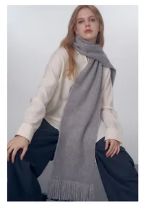 Dettaglio della sciarpa in maglia grigio chiaro con trama a coste e frange decorative