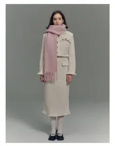 Close-up of soft pink wool blend scarf with fringe tassels on an elegant tweed outfit