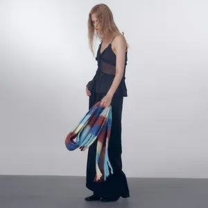 Woman wearing black high-waisted pants and a gradient colorful plaid wool blend scarf
