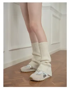 Detail of cream-colored wool blend leg warmers styled with silver retro sneakers