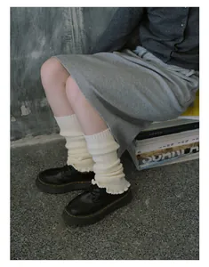 Detail of cream knit leg warmers with ribbed texture and ruffled edge styling